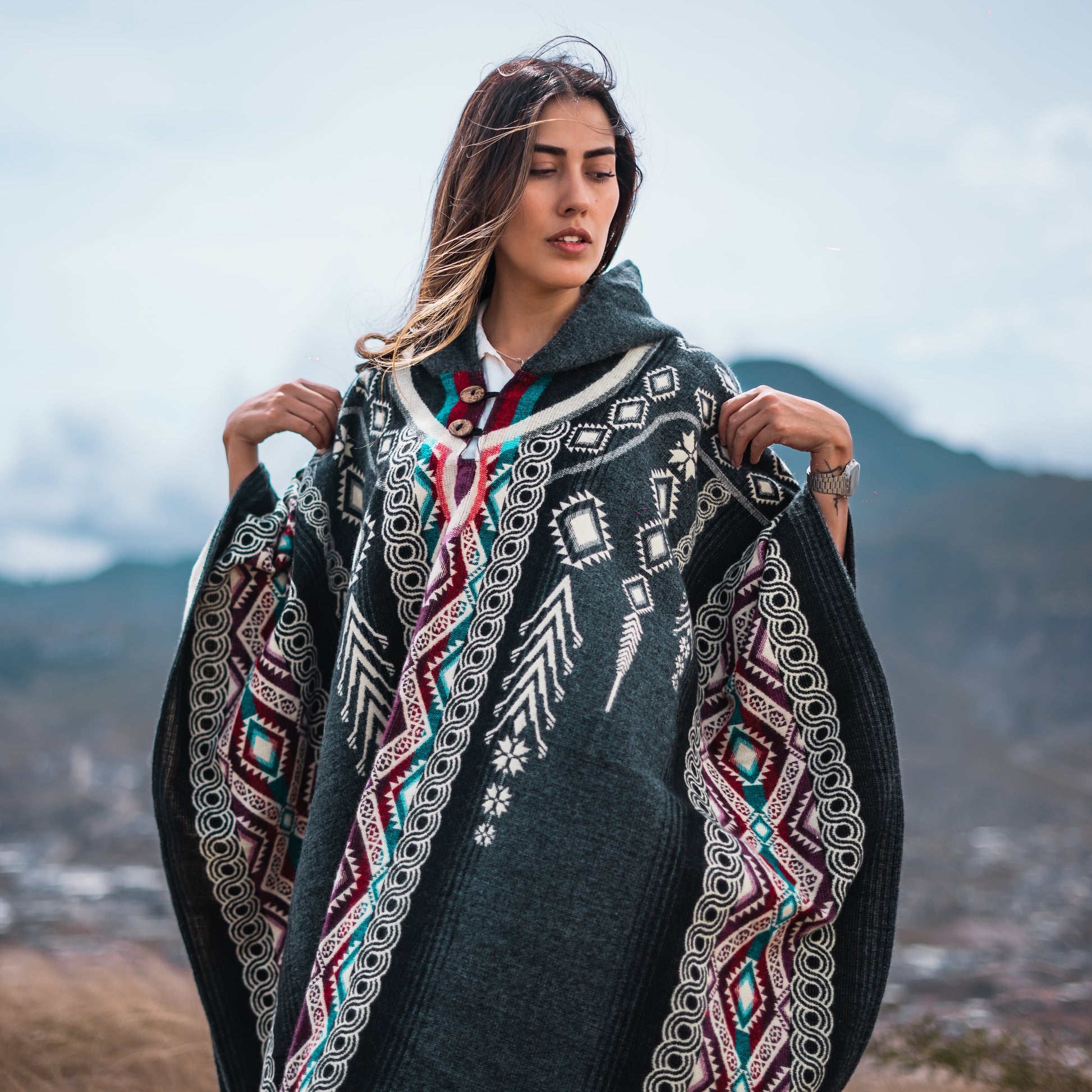 Woman wearing black and white Andean alpaca poncho with geometric patterns, handmade in the Andes, sustainable and hypoallergenic.